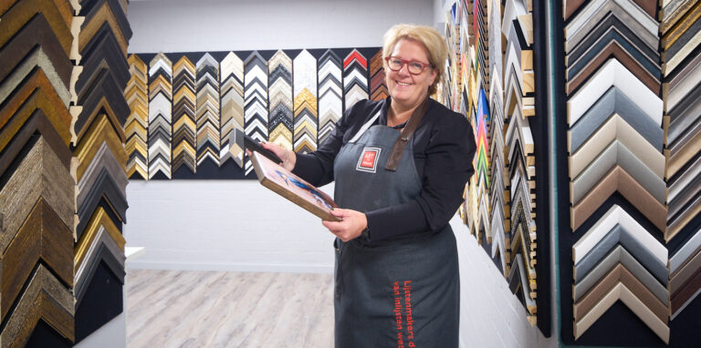 Natascha Heijnen met een handvol lijststalen bij de monsterwand in het atelier in Nederweert-Eind